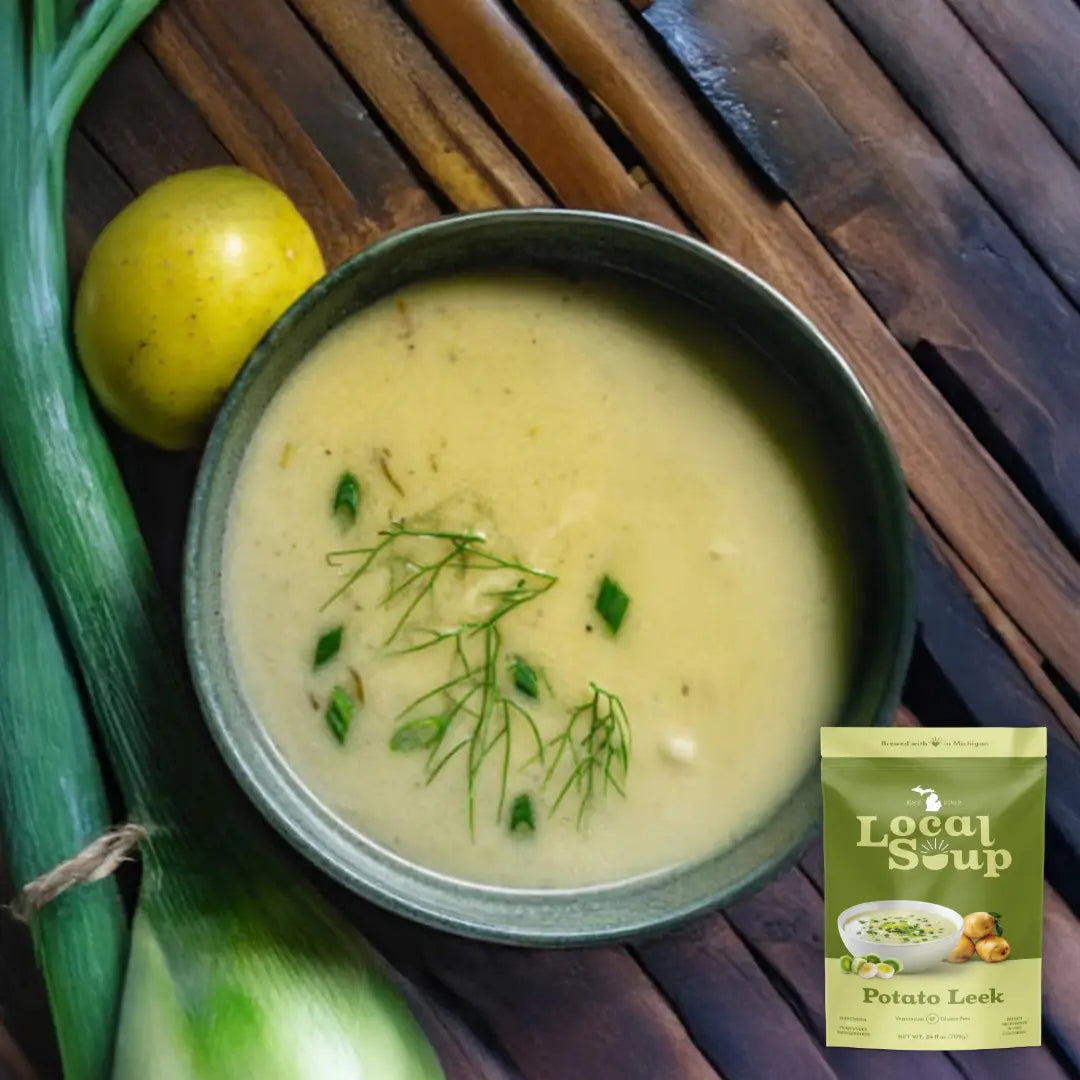 Bowl of potato leek soup with a package labeled 'Local Soup' on a wooden surface.