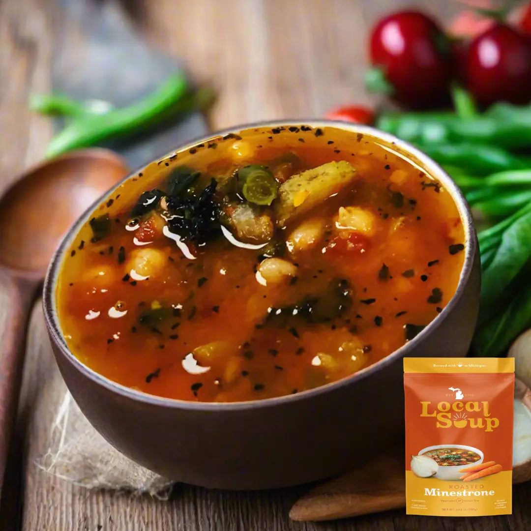 Bowl of minestrone soup with a packet labeled 'Local is the Soup' on a wooden background.
