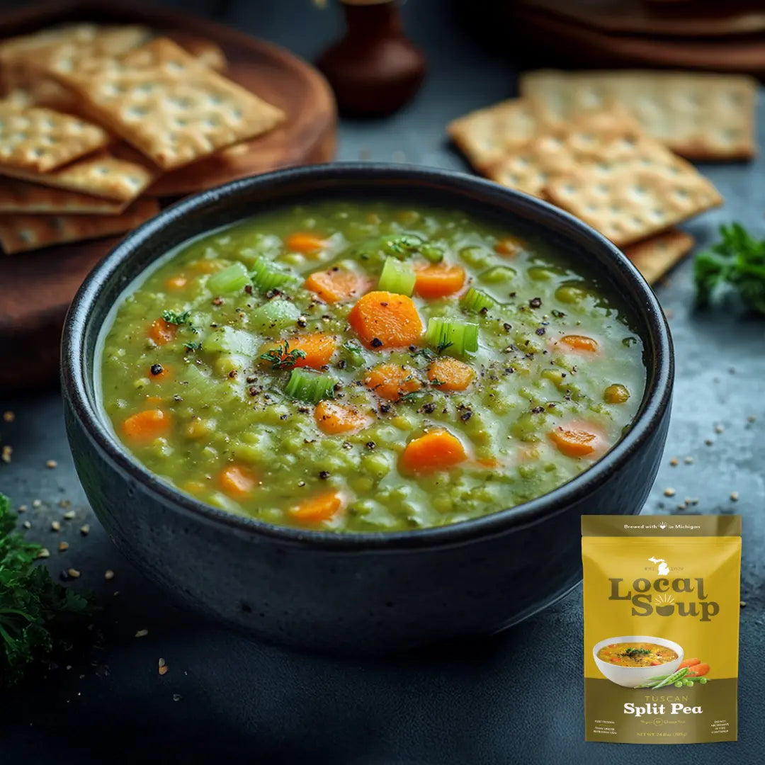 Bowl of split pea soup with crackers on a dark surface, featuring Local Soup packaging.